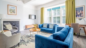 Un salon avec une cheminée, des canapés bleus, une table basse et un téléviseur.
