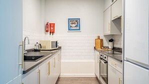 Une cuisine moderne avec des armoires blanches, des appareils en acier inoxydable et un four à micro-ondes posé sur le plan de travail.