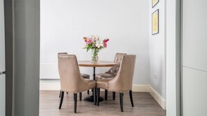 Un coin repas avec une table ronde et quatre chaises, un vase rempli de fleurs et des tableaux encadrés accrochés au mur.