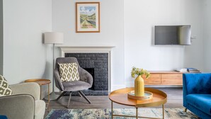 Un salon moderne avec une cheminée, un téléviseur à écran plat et un canapé bleu.