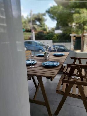 An outdoor dining area with a wooden table set for two, surrounded by wooden chairs. - GTD35501 - Unique Villa in Voula Riviera (Vari-Voula-Vouliagmeni)