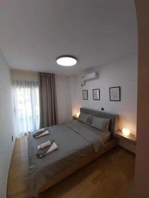 A modern bedroom with a large bed, a ceiling light, an air conditioning unit, and framed pictures on the wall. - GTD35501 - Unique Villa in Voula Riviera (Vari-Voula-Vouliagmeni)
