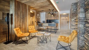 A lobby with wooden paneling, a reception desk, and a stone wall. - Chalet Hôtel Turquoise (La Plagne-Tarentaise)