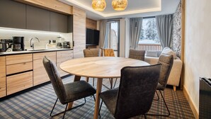 A modern kitchen with a round dining table, two pendant lights, and a sofa set. - Chalet Hôtel Turquoise (La Plagne-Tarentaise)