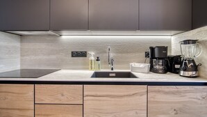 A modern kitchen with a sleek design, featuring a stainless steel sink, a coffee maker, and a blender. - Chalet Hôtel Turquoise (La Plagne-Tarentaise)