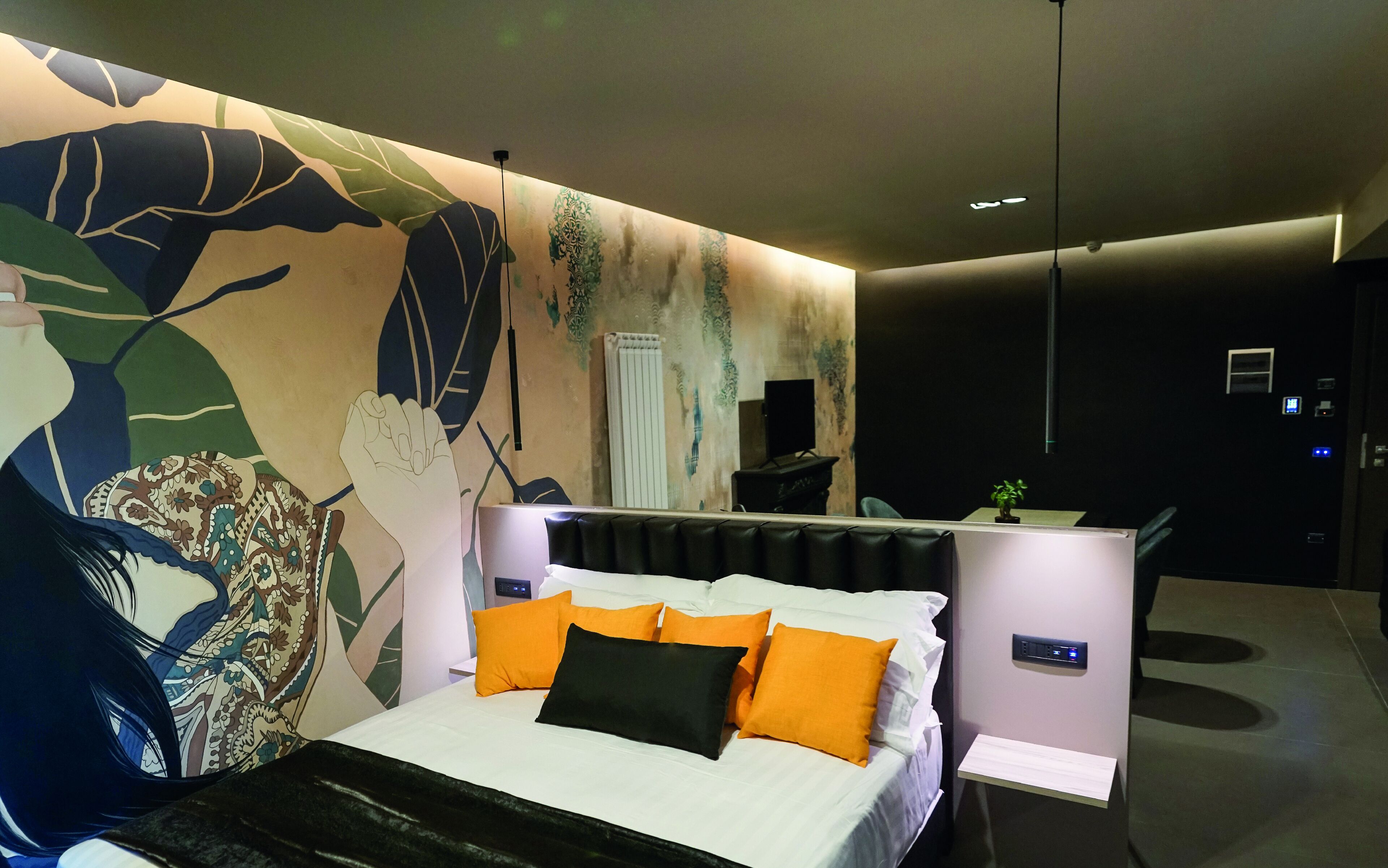 A modern bedroom with a large bed, a desk, and a mural on the wall.