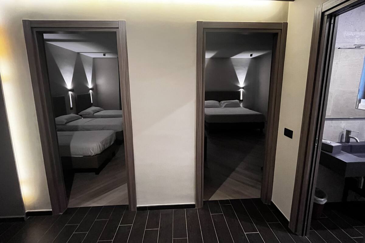 A hotel room with two beds, a bathroom, and a mirror.