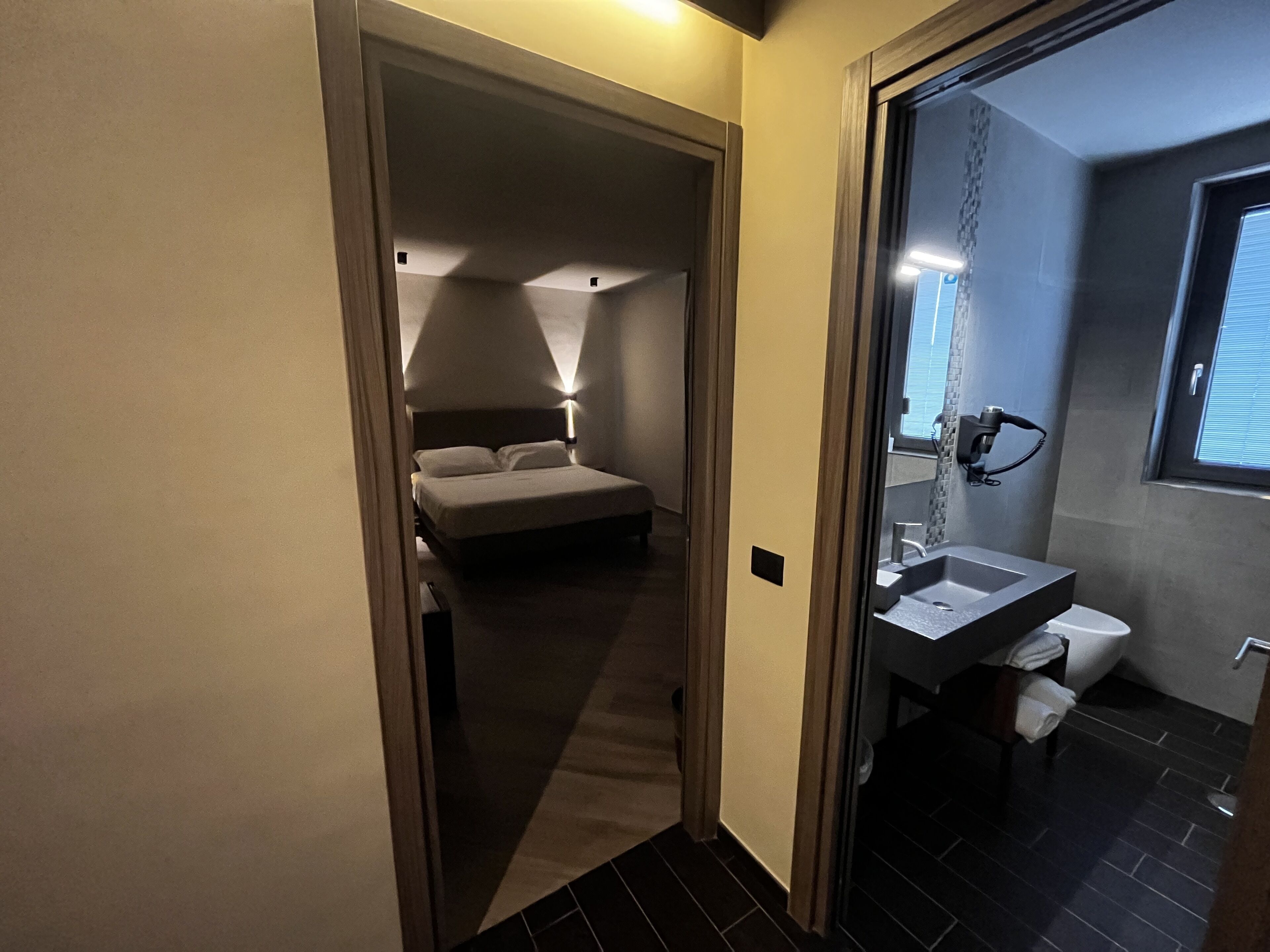 A hotel room with a bed, a bathroom with a sink and toilet, and a window.