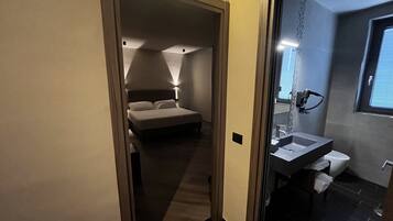 A hotel room with a bed, a bathroom with a sink and toilet, and a window.