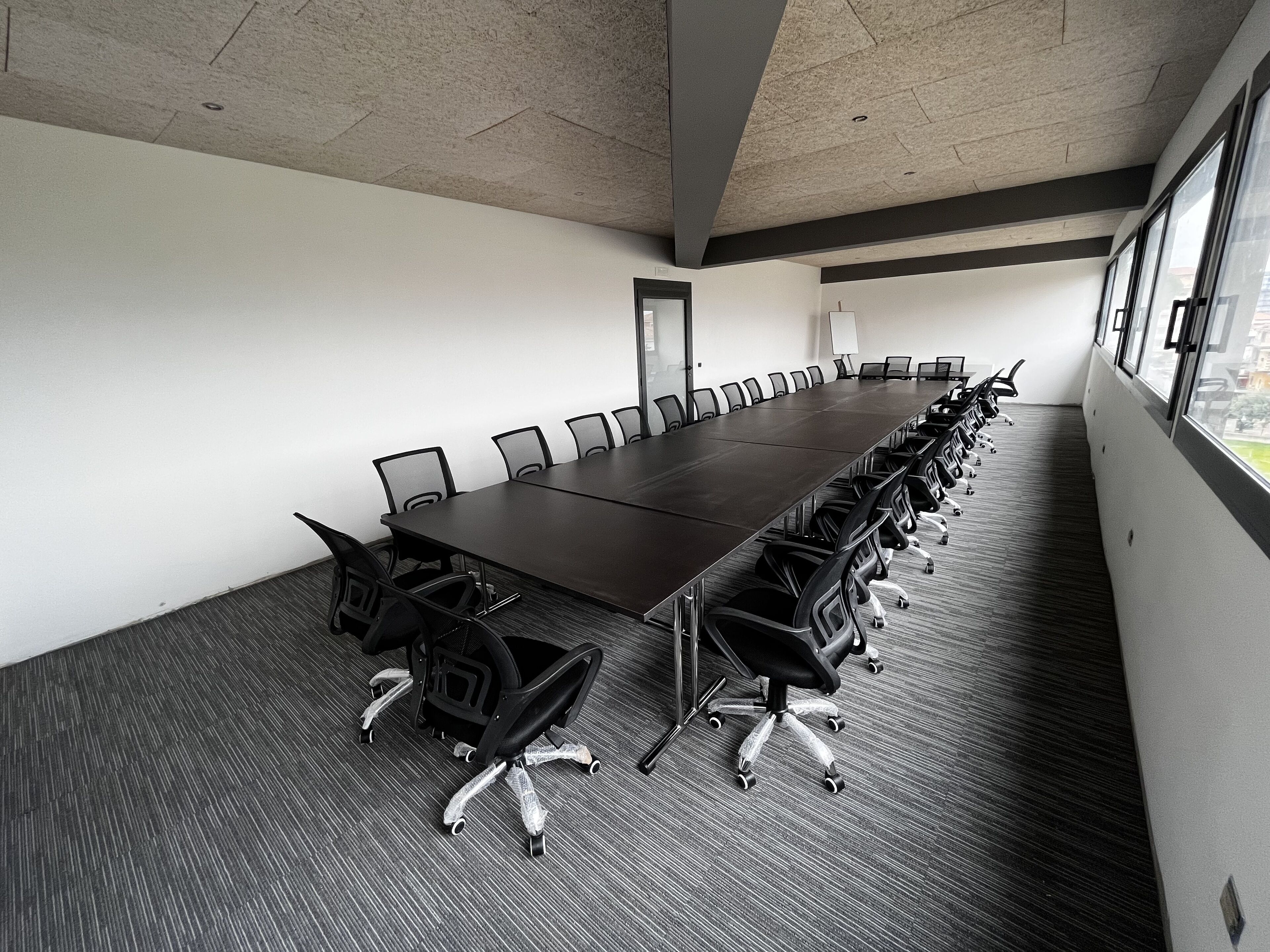 A conference room with a long table, chairs, and a carpeted floor.