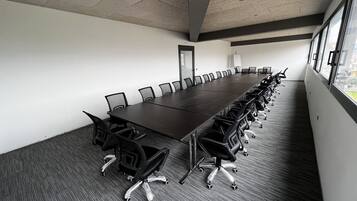 A conference room with a long table, chairs, and a carpeted floor.