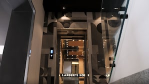 An elevator with a modern design, featuring geometric patterns and a sign that reads "LAMBERTI HOME".