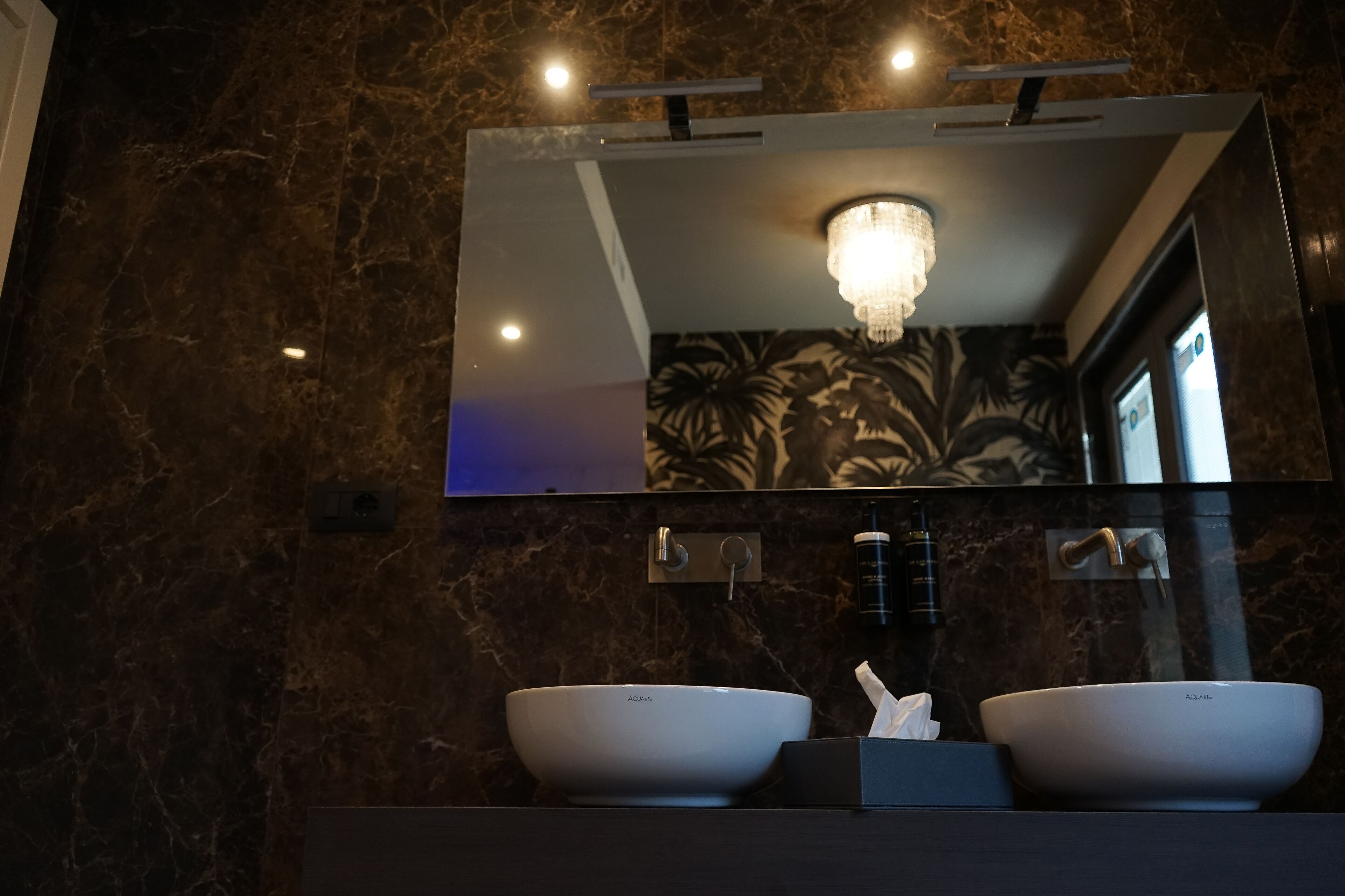 A bathroom with two white sinks, a mirror, and a chandelier.