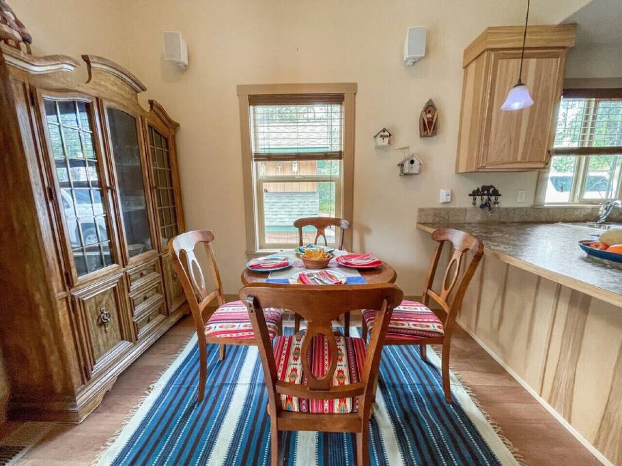 Een eethoek met een houten tafel, stoelen en een gestreept tapijt.