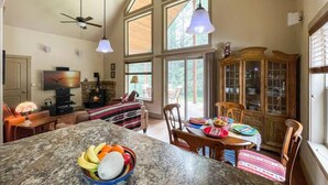 A spacious kitchen with a large island, a dining area with wooden chairs, and a fireplace. - Private Cabin at the Foot of the Mountains (Donnelly)