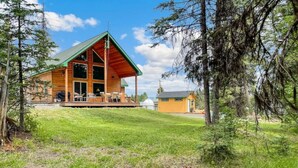 A wooden cabin with a porch, surrounded by trees and a grassy area. - Private Cabin at the Foot of the Mountains (Donnelly)