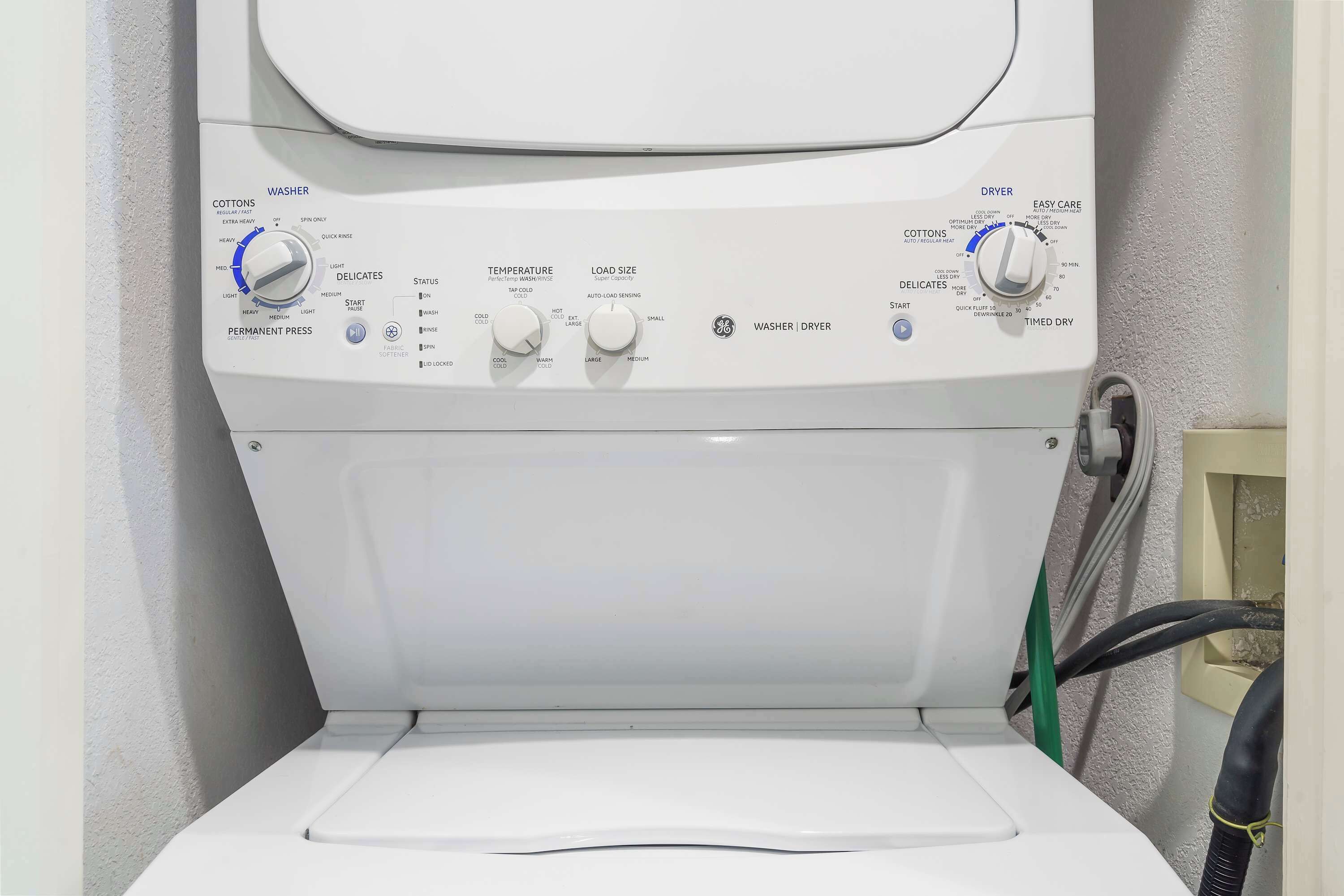 Vista frontal de uma máquina de lavar roupa com botões de controle para temperatura, tamanho da carga e configurações de centrifugação.