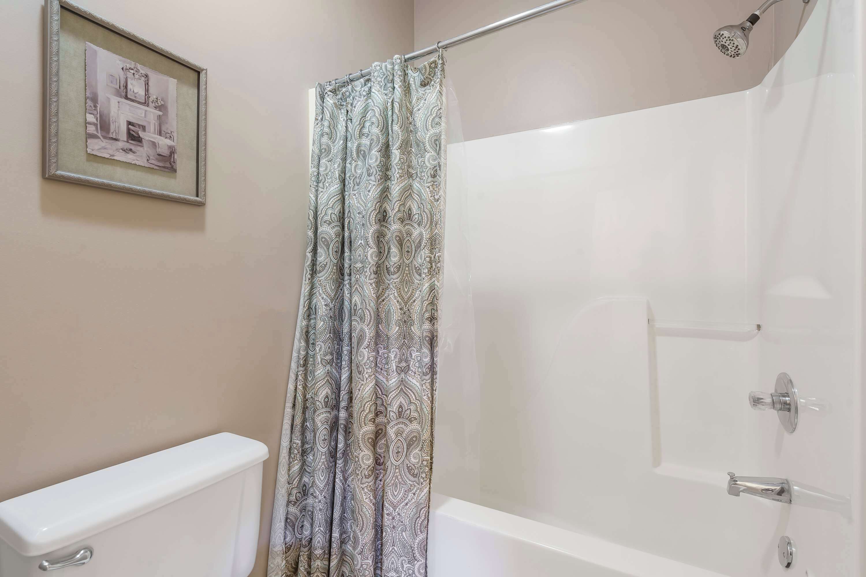 Un baño con inodoro, ducha con puerta de vidrio y un cuadro en la pared.
