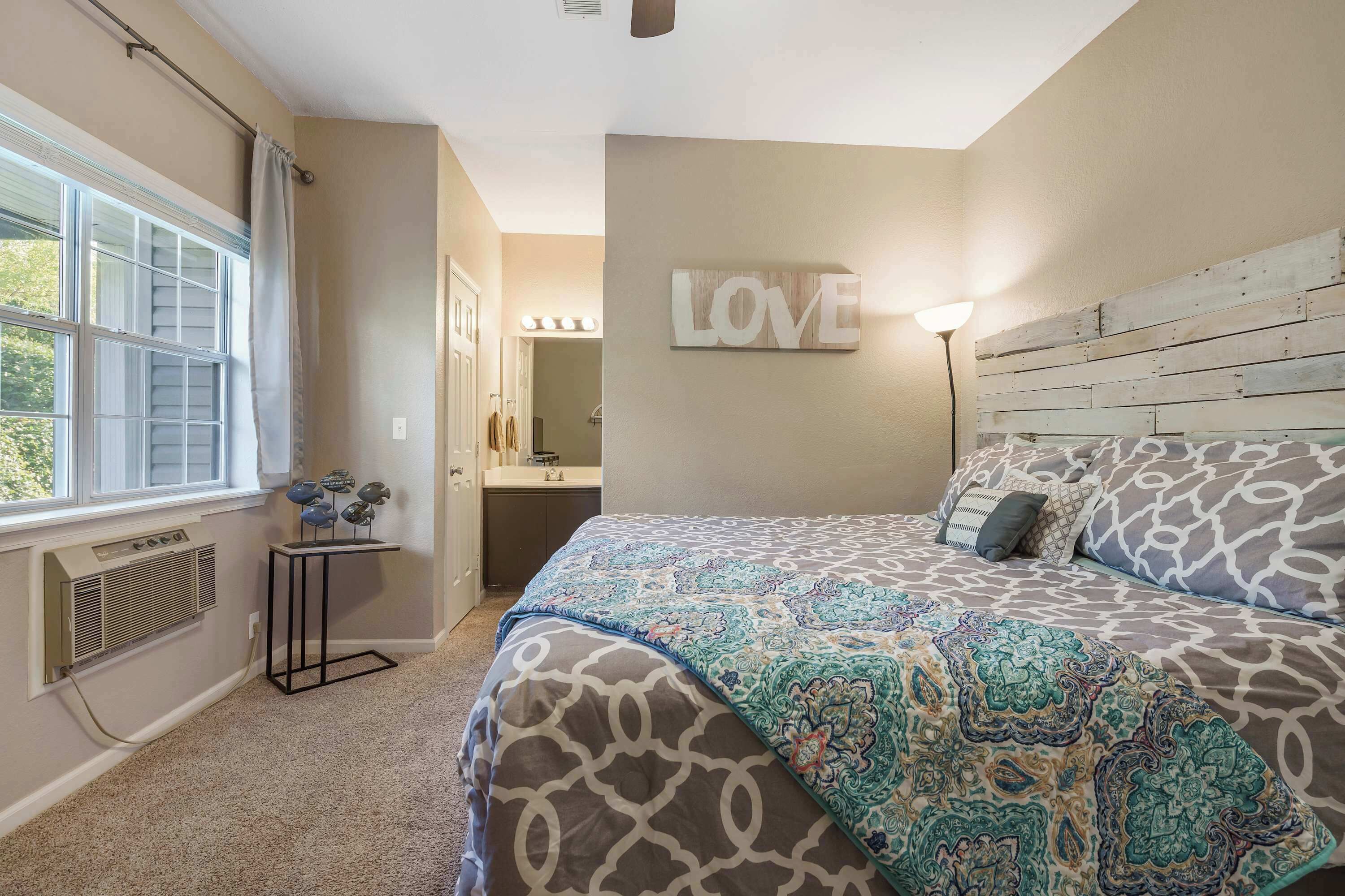 A bedroom with a large bed, a vanity with a mirror, and a 'LOVE' sign on the wall.