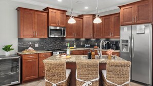 A modern kitchen with wooden cabinets, stainless steel appliances, and a central island with bar stools.