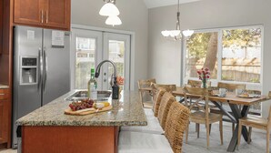 A kitchen with a granite countertop, stainless steel appliances, wooden cabinets, and a dining area with a table and chairs.