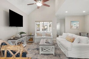 Relax in this stylish living room with a high ceiling, flat-screen TV, and comfortable sofa set.