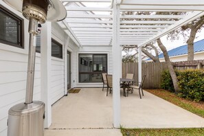 Relax in the shaded patio area with a table and two chairs, surrounded by a well-maintained garden.