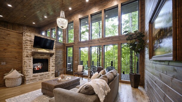 Una sala de estar acogedora con chimenea de piedra, ventanas amplias y un espacio de descanso confortable.
