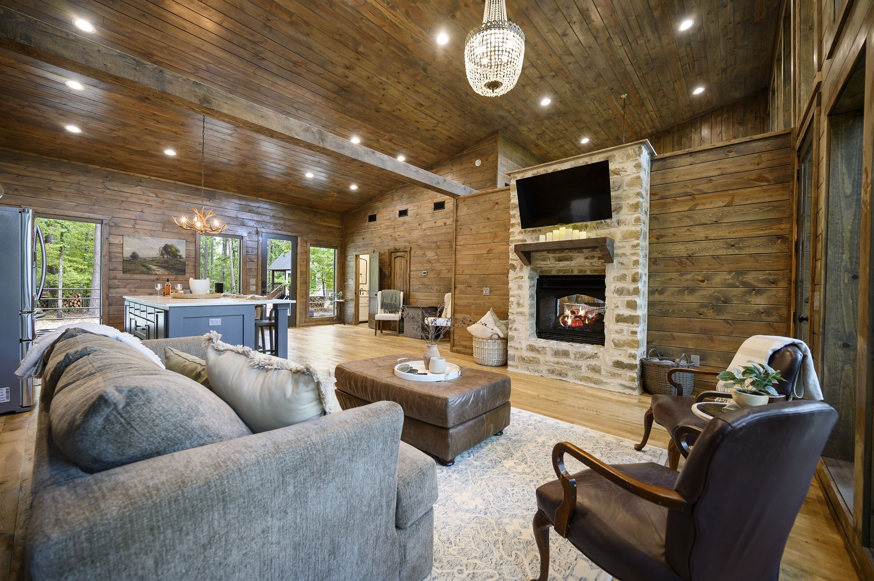 A spacious living room with a fireplace, wooden ceiling, and a cozy seating area.