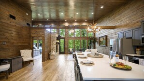 Una cocina amplia con paredes de madera, una isla grande y vistas a zonas verdes a través de las ventanas.
