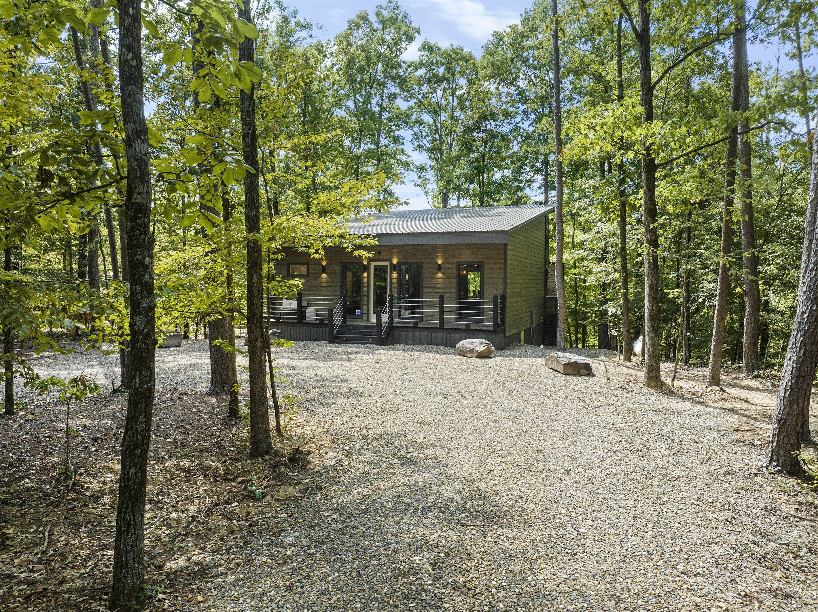 Un chalet doté d’une allée en gravier, d’une terrasse en bois et d’un espace salon abrité.