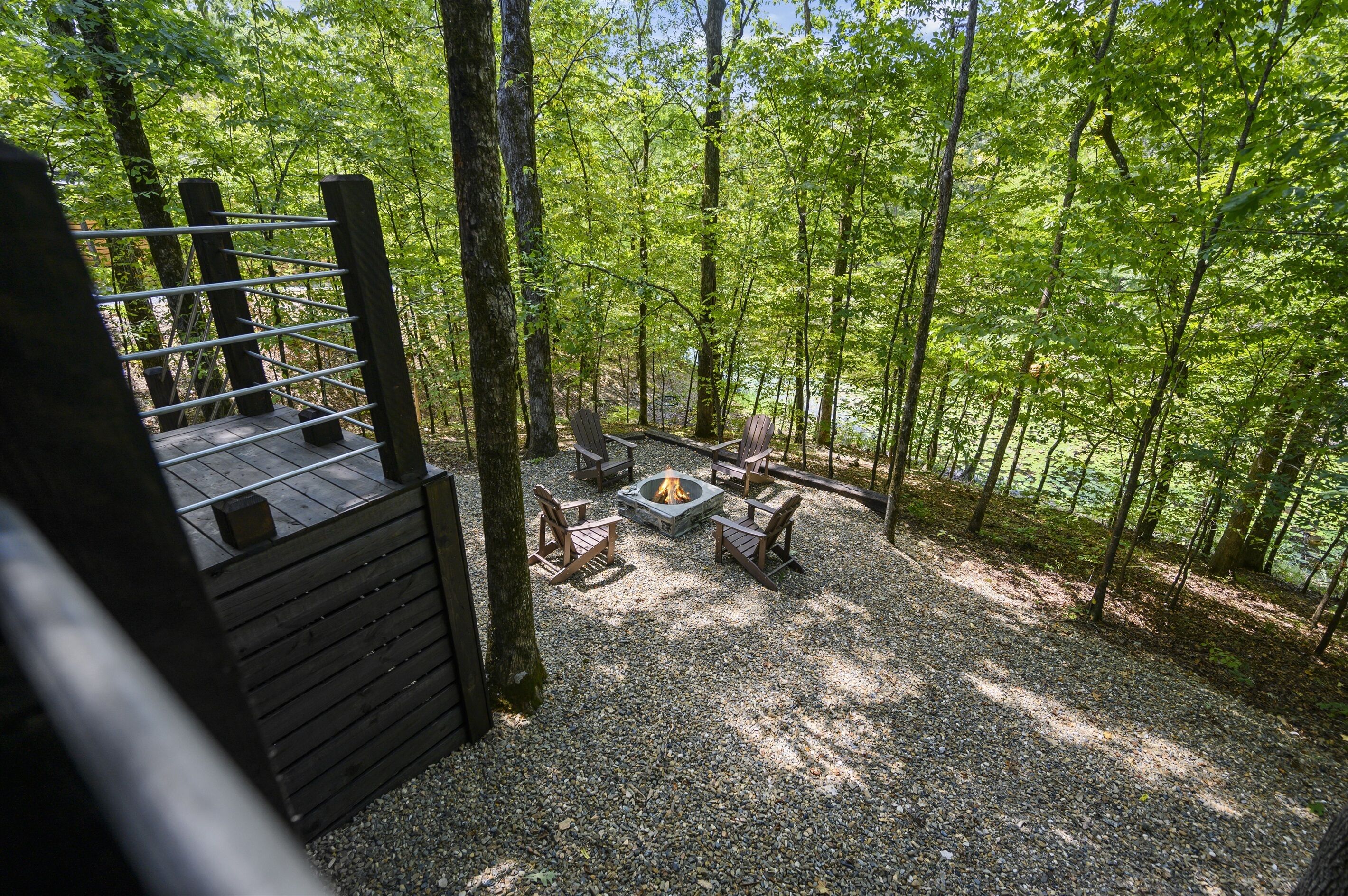 A forested area with a fire pit and seating.