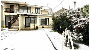 Ein zweistöckiges Haus mit Balkon, Treppe und einem schnee bedeckten Garten.