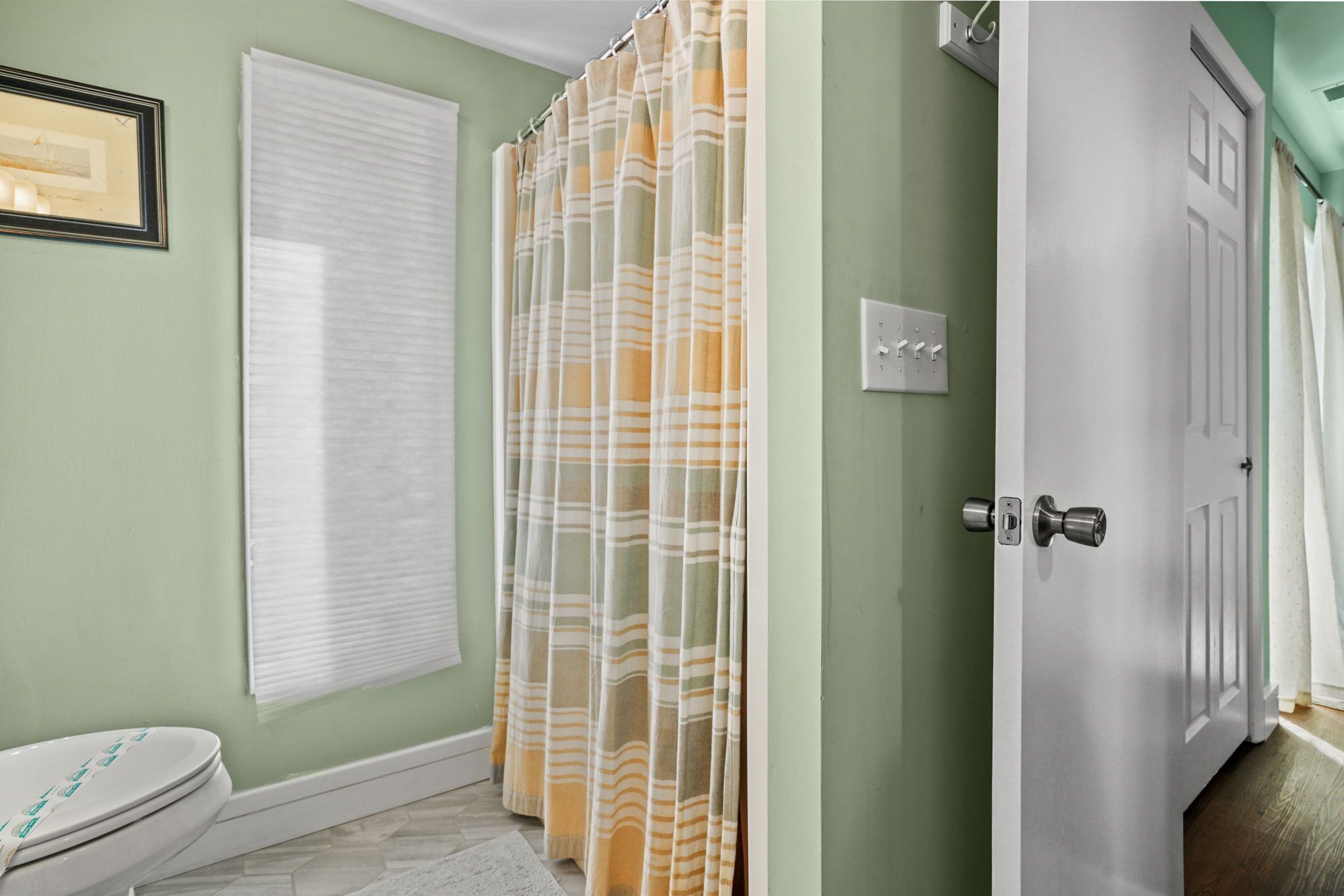 Un baño con inodoro, cortina de ducha y puerta.