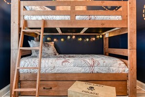 Uma cama beliche com escada, cabeceira com luzes de fada, e uma caixa com a etiqueta "The Lazy Pirate".