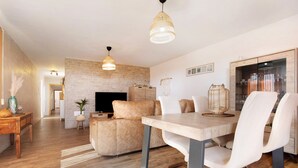 Uma sala de estar moderna com sofá, mesa de jantar, cadeiras, televisão e parede de tijolos.