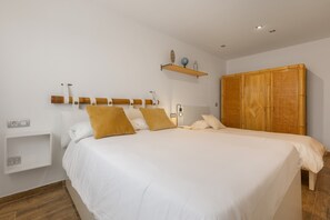 Una camera da letto con un letto grande, un armadio, una mensola con oggetti decorativi e un comodino.