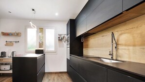 Uma cozinha moderna com painel de madeira, armários pretos e uma pia de aço inoxidável.