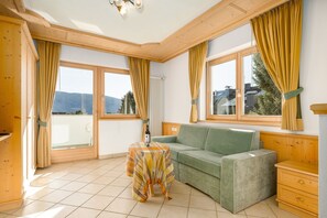 A room with a sofa, a small table, and a window with curtains.