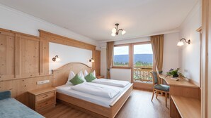 Une chambre à coucher avec un lit en bois, un bureau, une chaise et une vue sur l’extérieur.