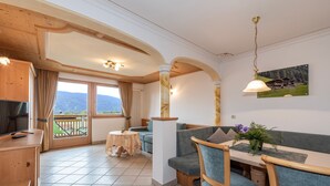 Une pièce avec un plafond en bois, un coin repas avec une table et des chaises, un canapé et une vue par la fenêtre.