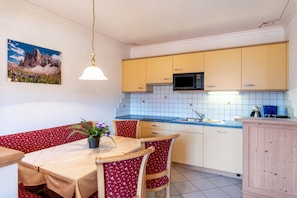 A compact kitchen with yellow cabinets, a microwave, and a blue countertop.