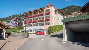 Un hôtel à plusieurs étages doté de balcons, d’un parking et offrant une vue sur les montagnes.