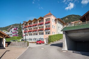 Un hôtel à plusieurs étages doté de balcons, d’un parking et offrant une vue sur les montagnes.