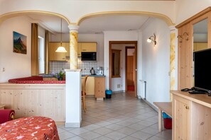 Une pièce comprenant un lit, un bureau, une chaise, un petit coin cuisine et un téléviseur.