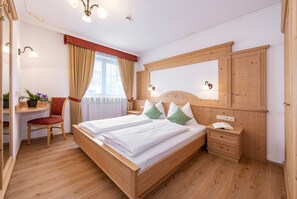 Un dormitorio ordenado con cama de madera, mesitas de noche, escritorio y espejo.