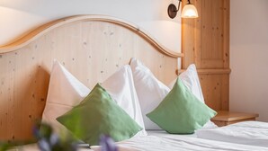 Un lit bien fait, avec des oreillers blancs et verts, une tête de lit en bois et une petite table de chevet.