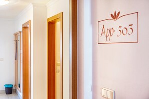 Un pasillo con puertas de madera y un cartel en la pared que indica 'App 305'.