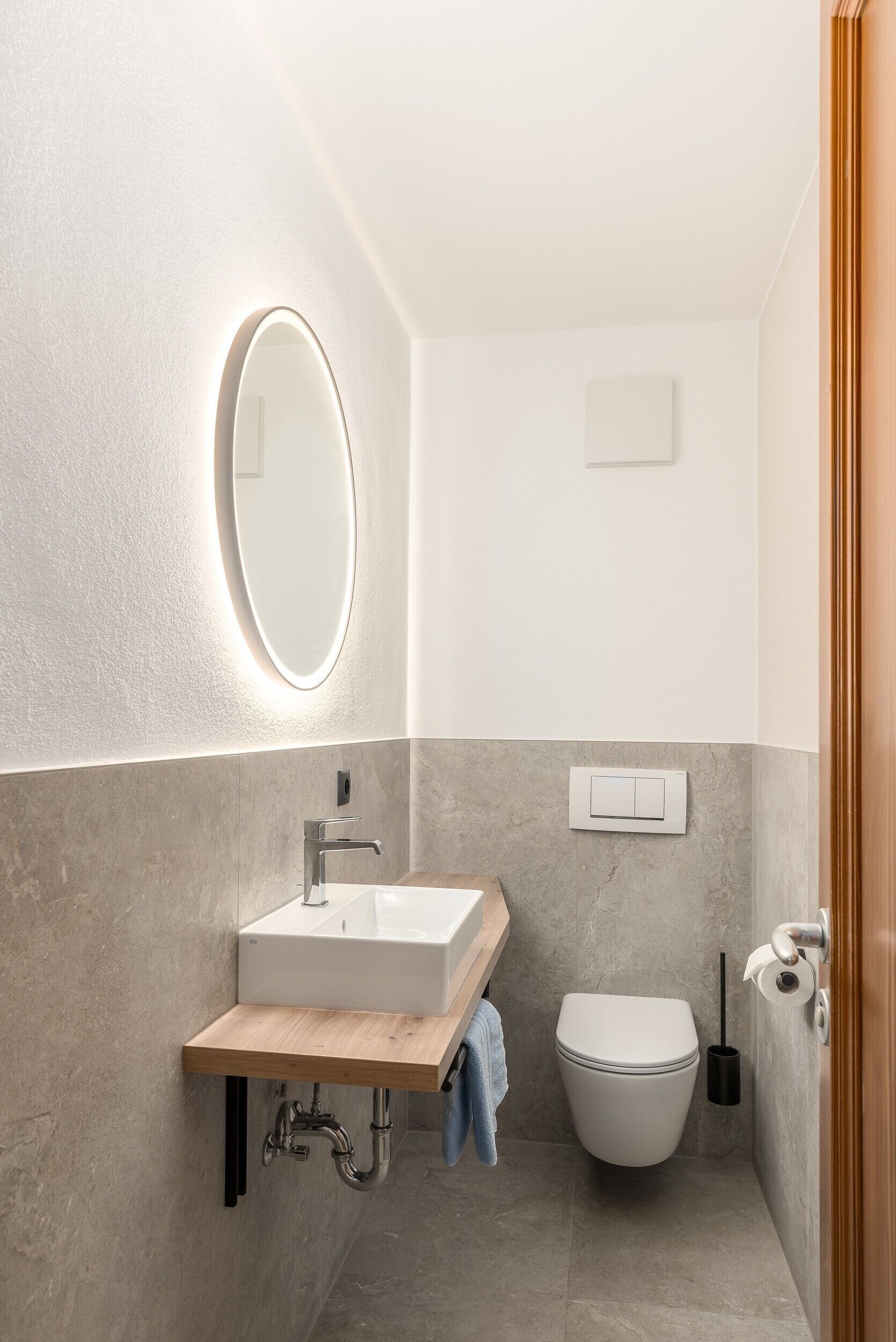 A modern bathroom with a white sink, mirror, and toilet.