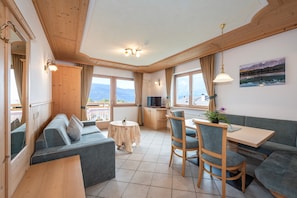 A cozy room with a sofa, dining table, chairs, a small round table, and a TV. - 'Residence Diana Apartment 303' with Mountain View, Balcony & Wi-Fi (Terenten)
